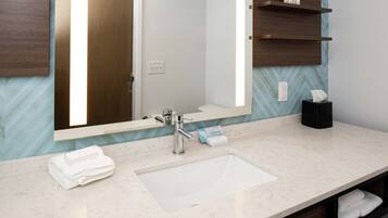 A bathroom with a large mirror, a sink, and a towel rack.