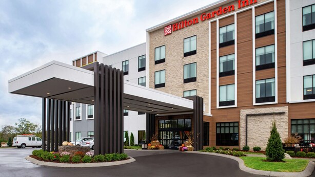 Een Hilton Garden Inn met een modern ontwerp, met een overdekte ingang, een parkeerplaats en een aangelegde tuin.