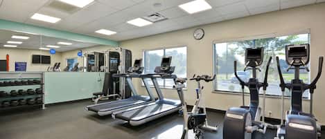 Un gimnasio con cintas de correr, elípticas y pesas libres.