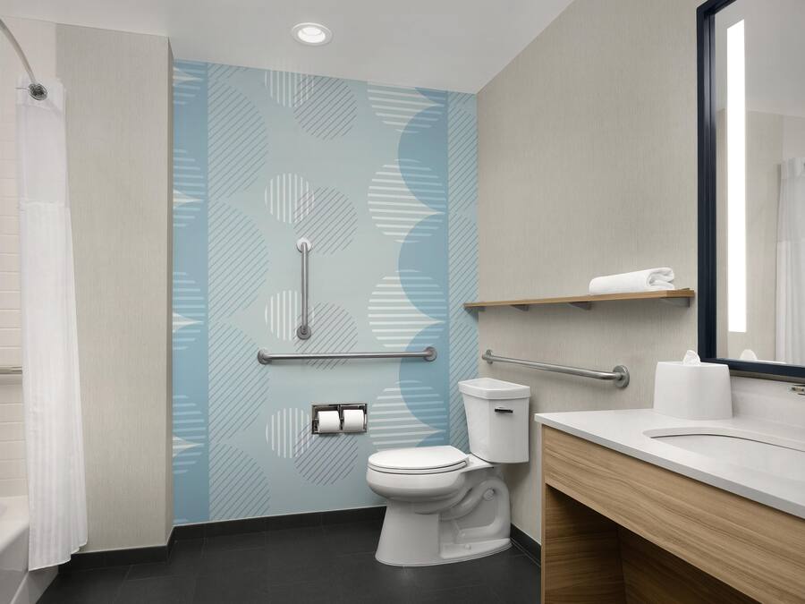 A modern bathroom with a shower, toilet, and sink, featuring a patterned wall and a mirror.