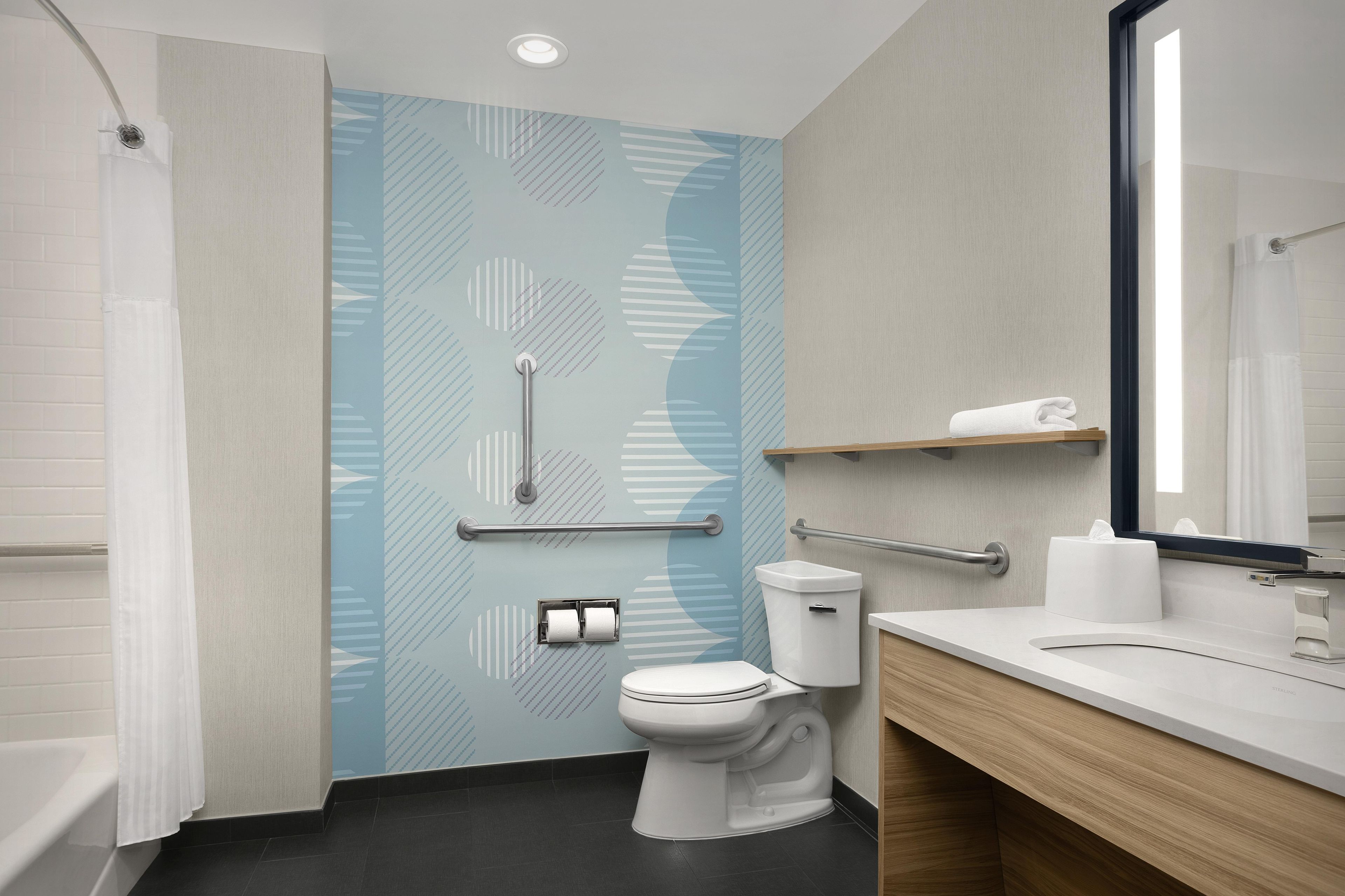 Un baño moderno con ducha, inodoro y lavabo, que destaca por un revestimiento de pared estampado y un espejo.