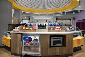 A self-service beverage station with a refrigerated display, a microwave, and a variety of drinks. - Tru by Hilton Fayetteville I-95, NC (Fayetteville)