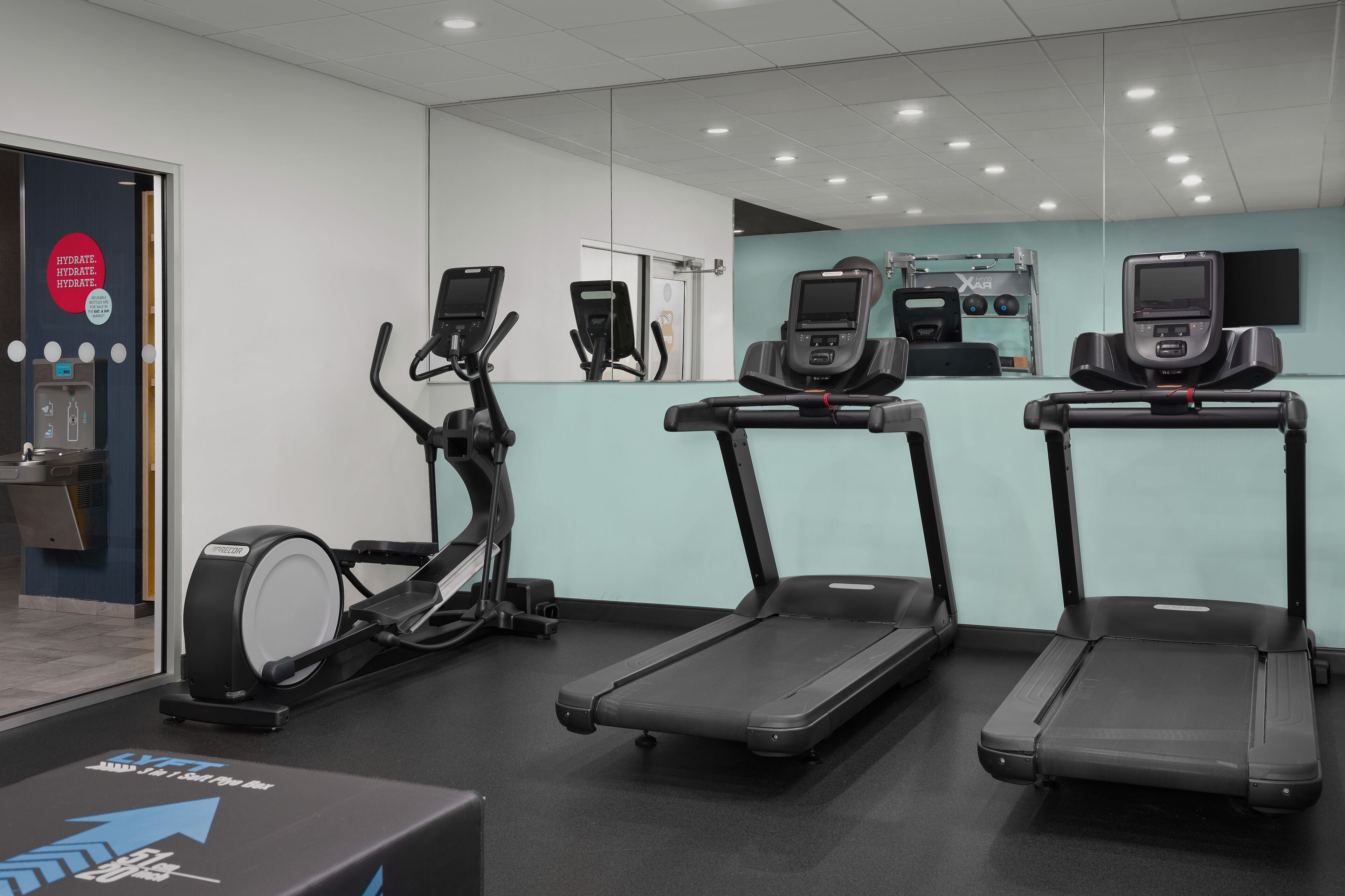Une salle de sport équipée de tapis de course, d’un vélo elliptique et d’un vélo d’appartement.