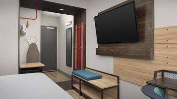 Quarto de hotel moderno com cama, um banco, uma mesa, TV e espelho.