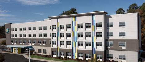 A modern multi-story building with a parking lot in front.
