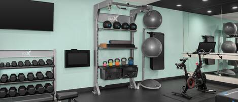 A gym with exercise equipment, including dumbbells, kettlebells, and an exercise bike.