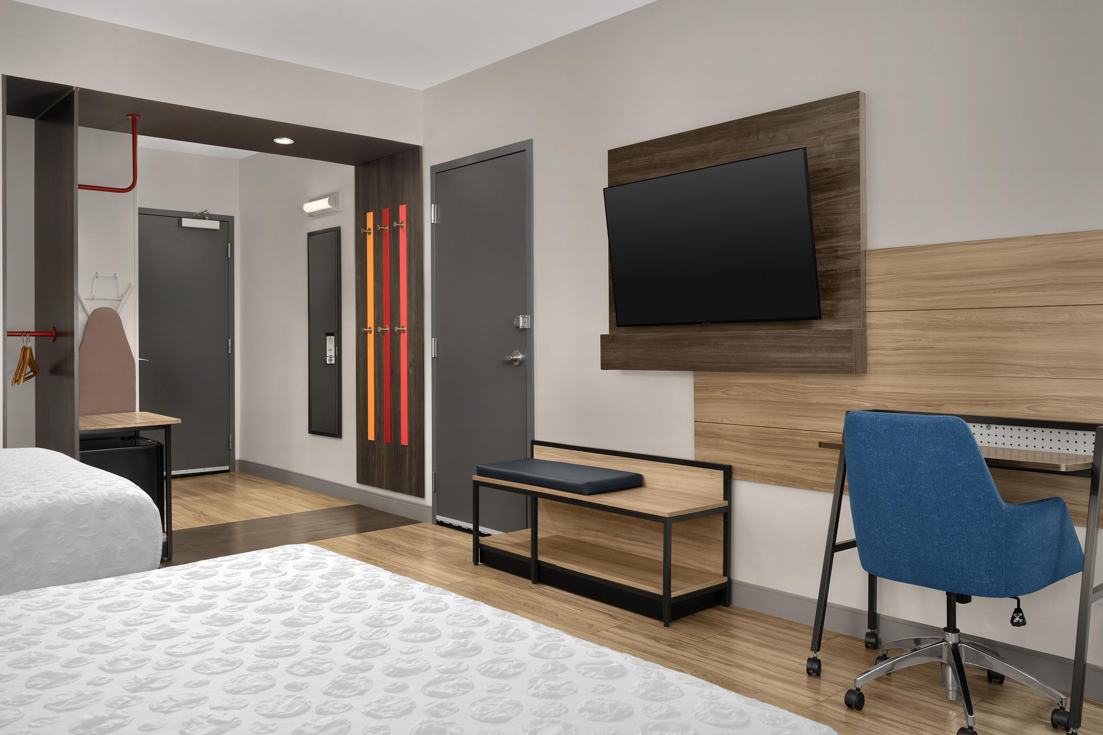 Una camera d'albergo con un letto, una scrivania con una sedia, una televisione e un armadio.
