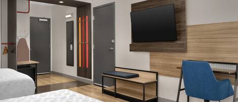 A hotel room with a bed, a desk with a chair, a television, and a wardrobe.
