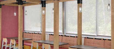 Comedor con vigas de madera, asientos acolchados e iluminación colgante.