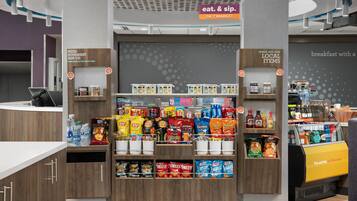 A snack kiosk with a variety of chips and snacks, a front desk area, and a sign indicating a 24/7 market.