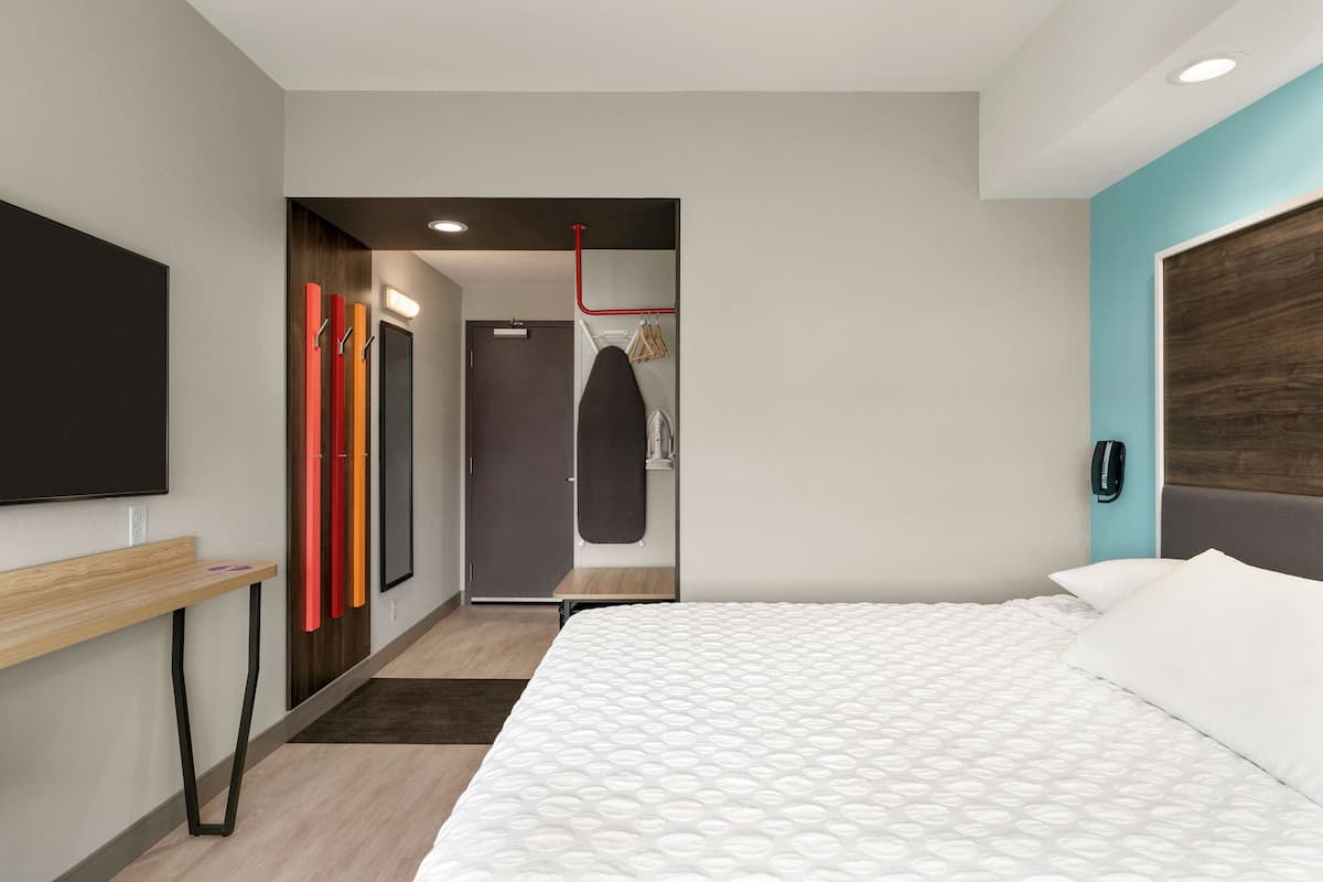 Una camera d'albergo moderna con un letto grande, una scrivania, una TV e un armadio con pomelli colorati.