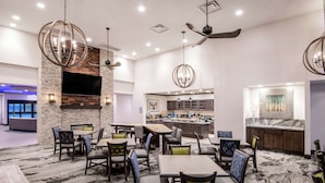A hotel lobby with a stone wall, a flat-screen TV, a bar area, and multiple seating arrangements.