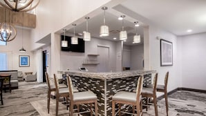 A modern kitchen with a central island, bar stools, pendant lighting, and a patterned floor.