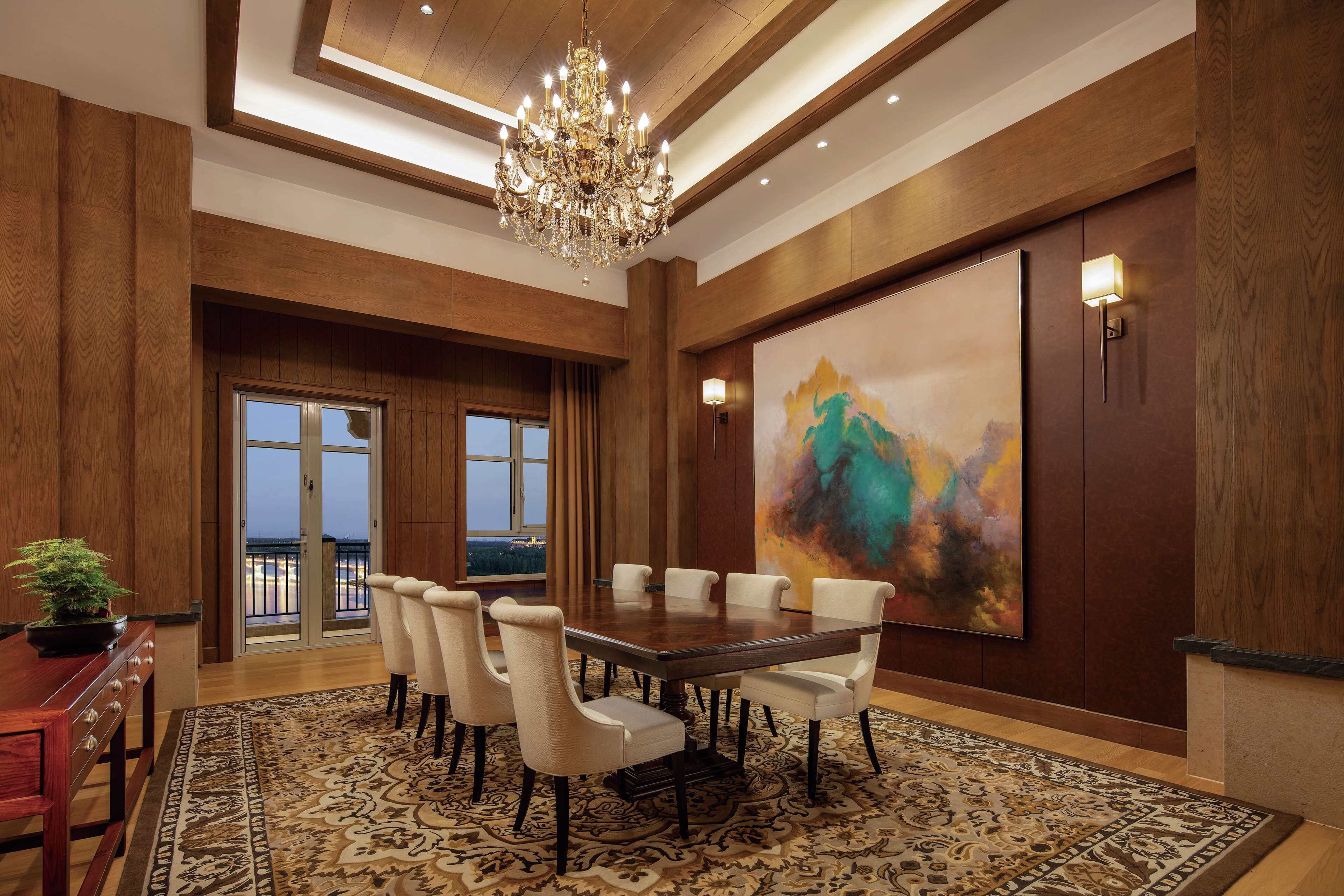 A spacious dining area with a large wooden table, six chairs, and a chandelier.