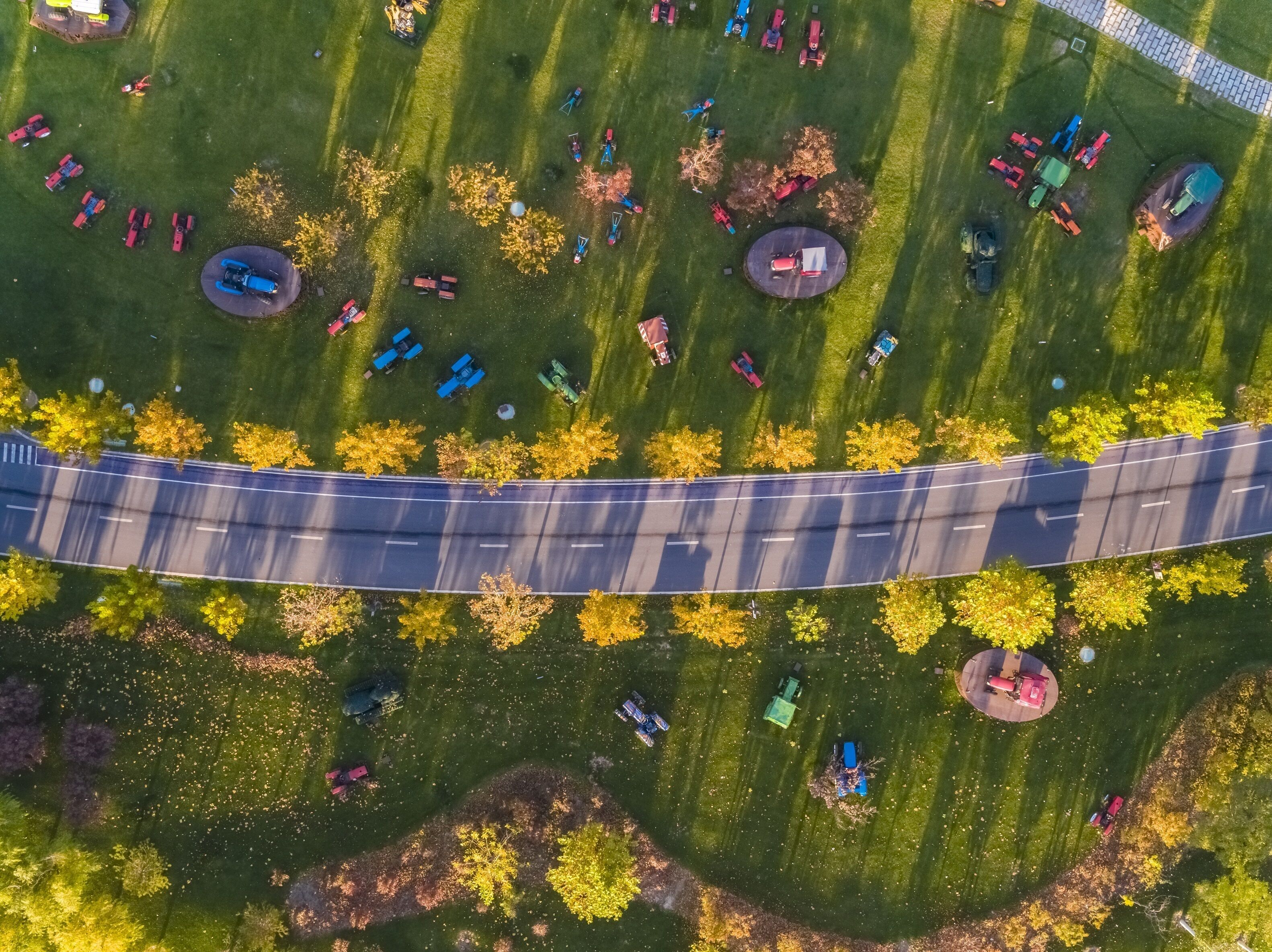 An aerial view of a parking lot with multiple vehicles and a curved road.