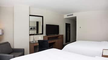 A hotel room with a bed, a desk with a chair, a television, and a mirror.