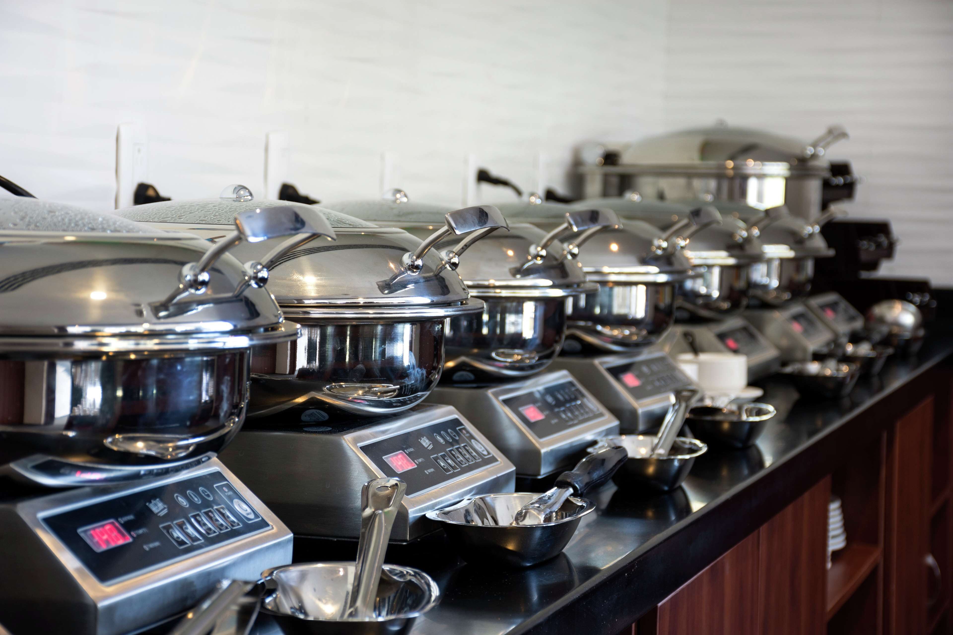 A buffet setup with multiple stainless steel serving stations, each equipped with a digital display and a spoon rest.