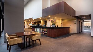 Un vestíbulo moderno con recepción, zona de estar y vistas al exterior.