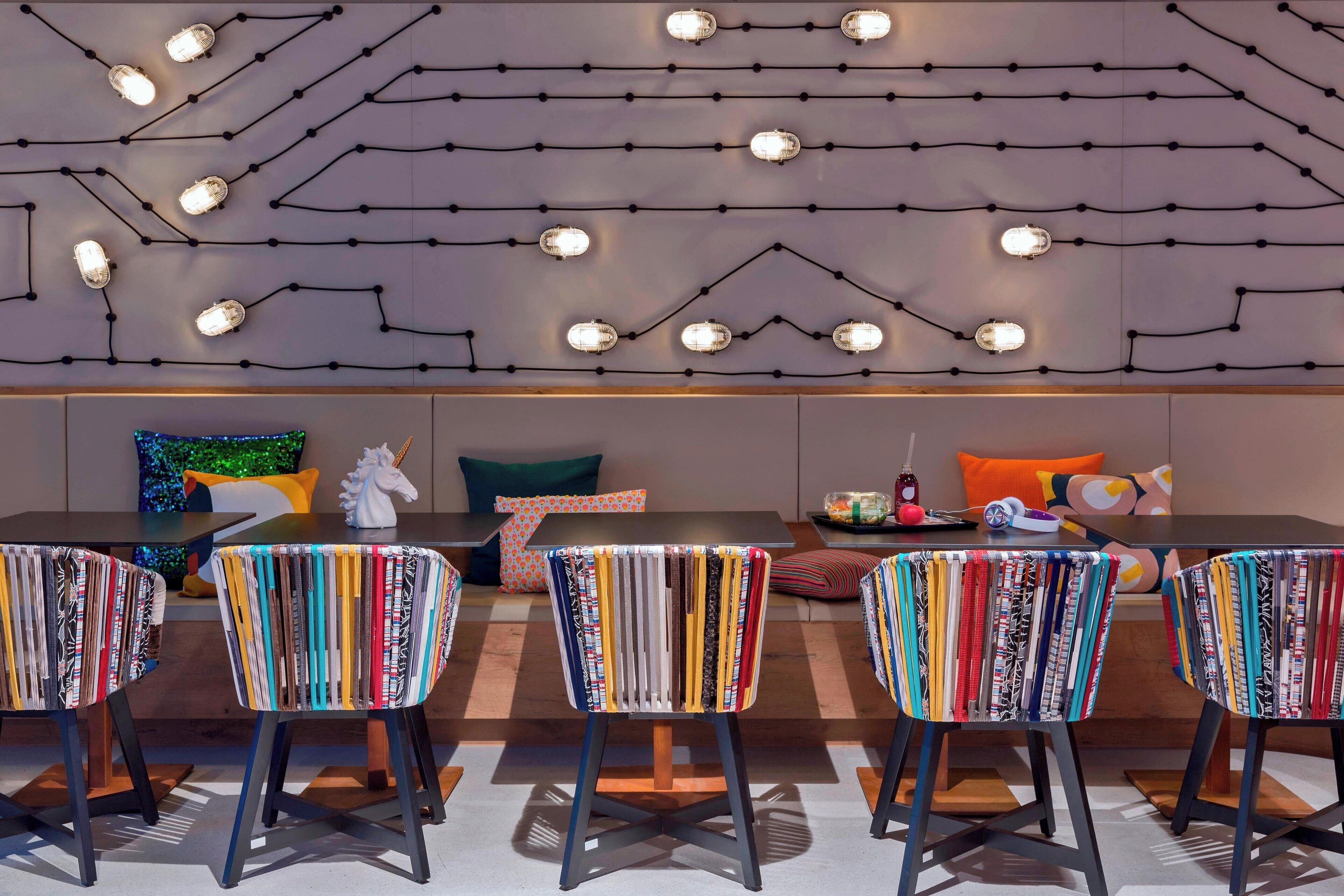 Een moderne eethoek met een lange tafel, gestreepte stoelen en een wandlamp.