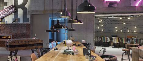 Un amplio y moderno salón con una larga mesa de madera, asientos cómodos e iluminación ambiental.