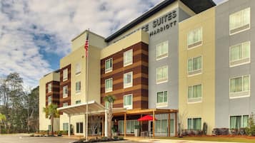 Guests can enjoy a comfortable stay at Marriott Suites, featuring a covered outdoor seating area and easy access to parking.