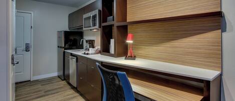 Una cucina moderna con elettrodomestici integrati, una parete d'accento in legno e una scrivania con sedia.