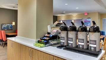 Una estación de café con varios dispensadores de café, un dispensador de bebidas y una variedad de cápsulas de café y snacks.