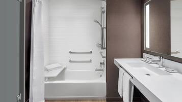 A modern bathroom with a bathtub, shower, and vanity.