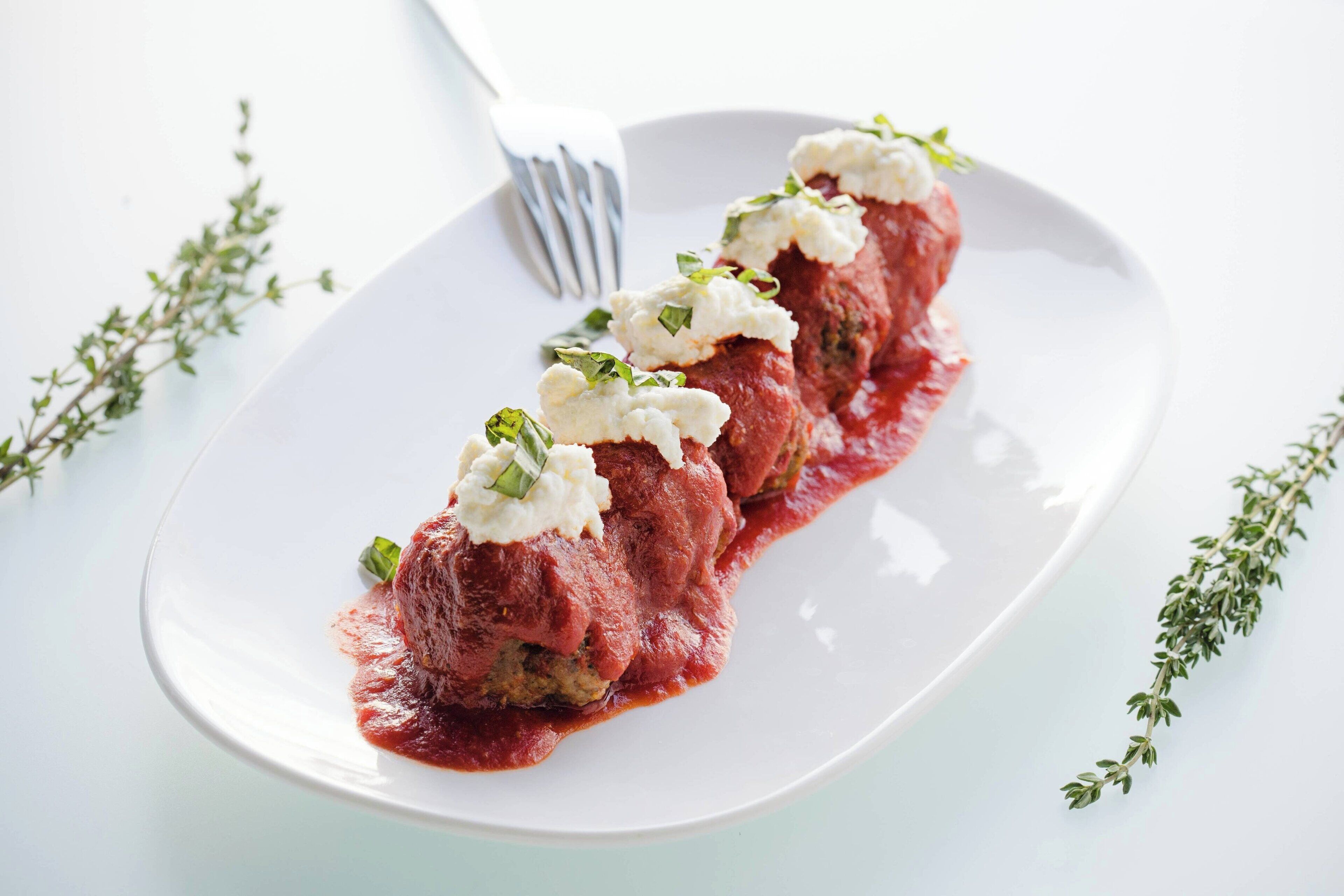 A plate of stuffed peppers with a creamy topping and a fork beside it.