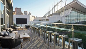 A rooftop terrace with outdoor seating, a large TV screen, and a city view. - AC Hotel Pittsburgh Downtown (Pittsburgh)
