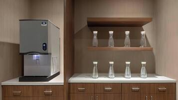 A kitchen with a water dispenser, wooden cabinets, and a countertop with glass bottles.
