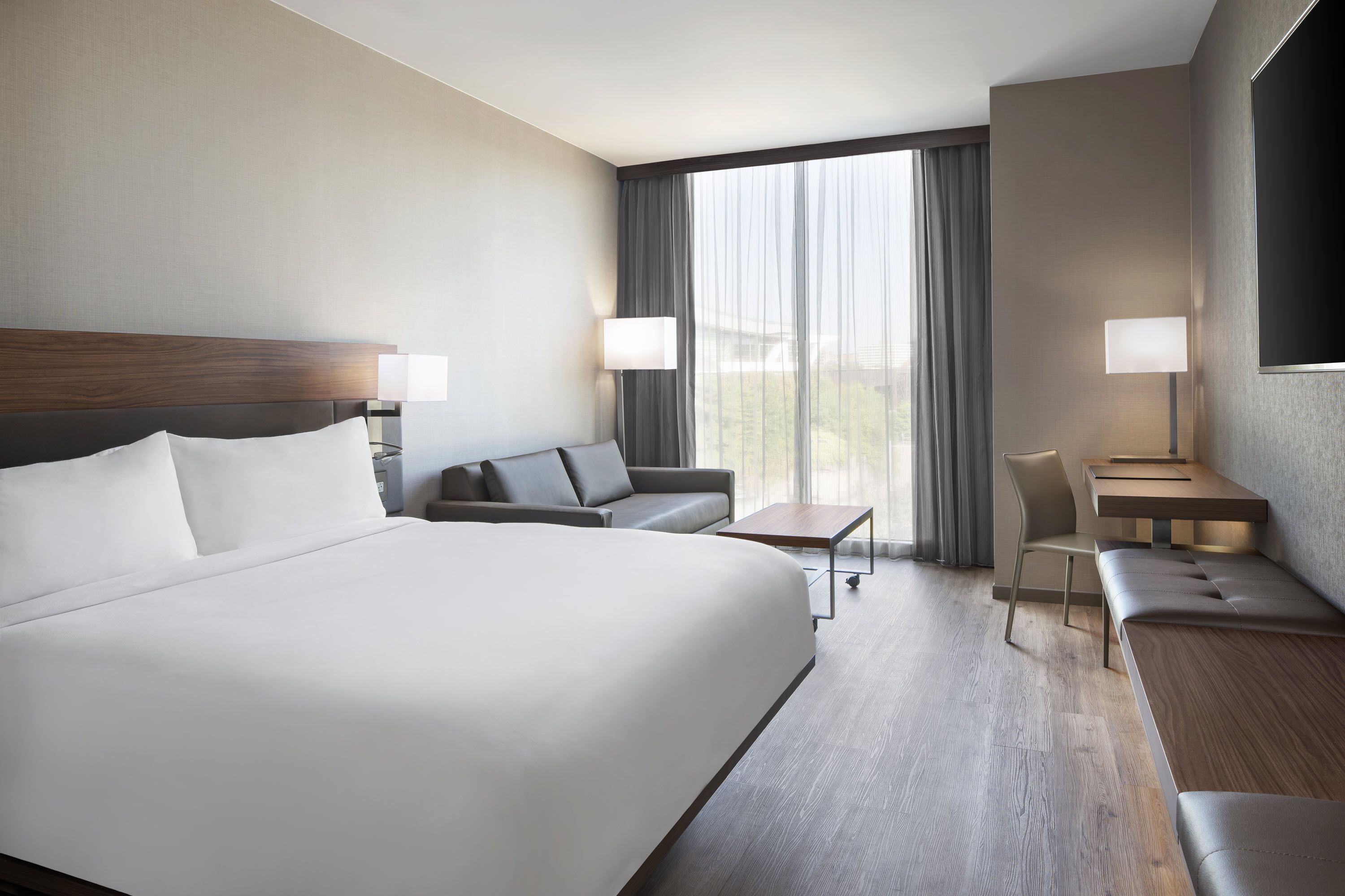 Quarto de hotel com uma cama grande, um sofá, uma escrivaninha e uma cadeira.