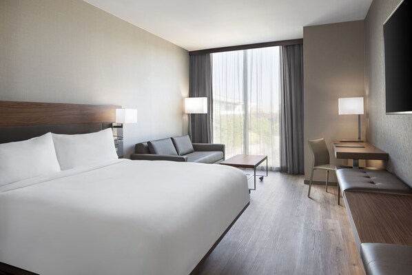 A hotel room with a large bed, a sofa, a desk, and a chair. - AC Hotel Pittsburgh Downtown (Pittsburgh)