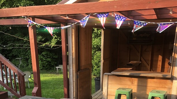 A wooden deck with a barbecue area, a covered seating area, and a small bar. - Gravity Inn Motel (Waymart)