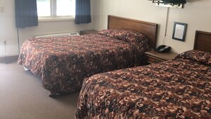 A hotel room with two beds, a window with curtains, a bedside lamp, and a framed certificate on the wall. - Gravity Inn Motel (Waymart)