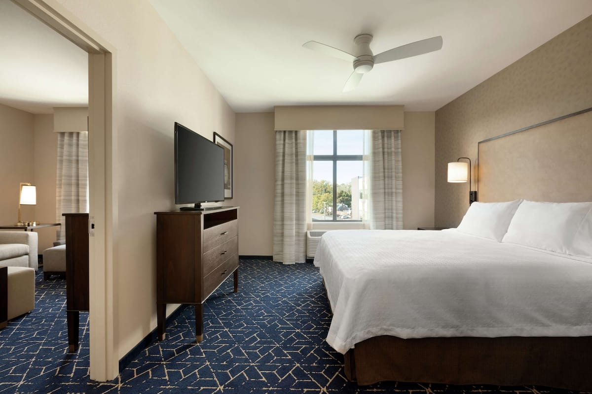 Een hotelkamer met een bed, een televisie, een bureau en een raam met gordijnen.