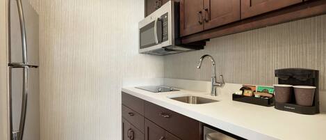 A modern kitchen with stainless steel appliances, a double sink, and a coffee station.