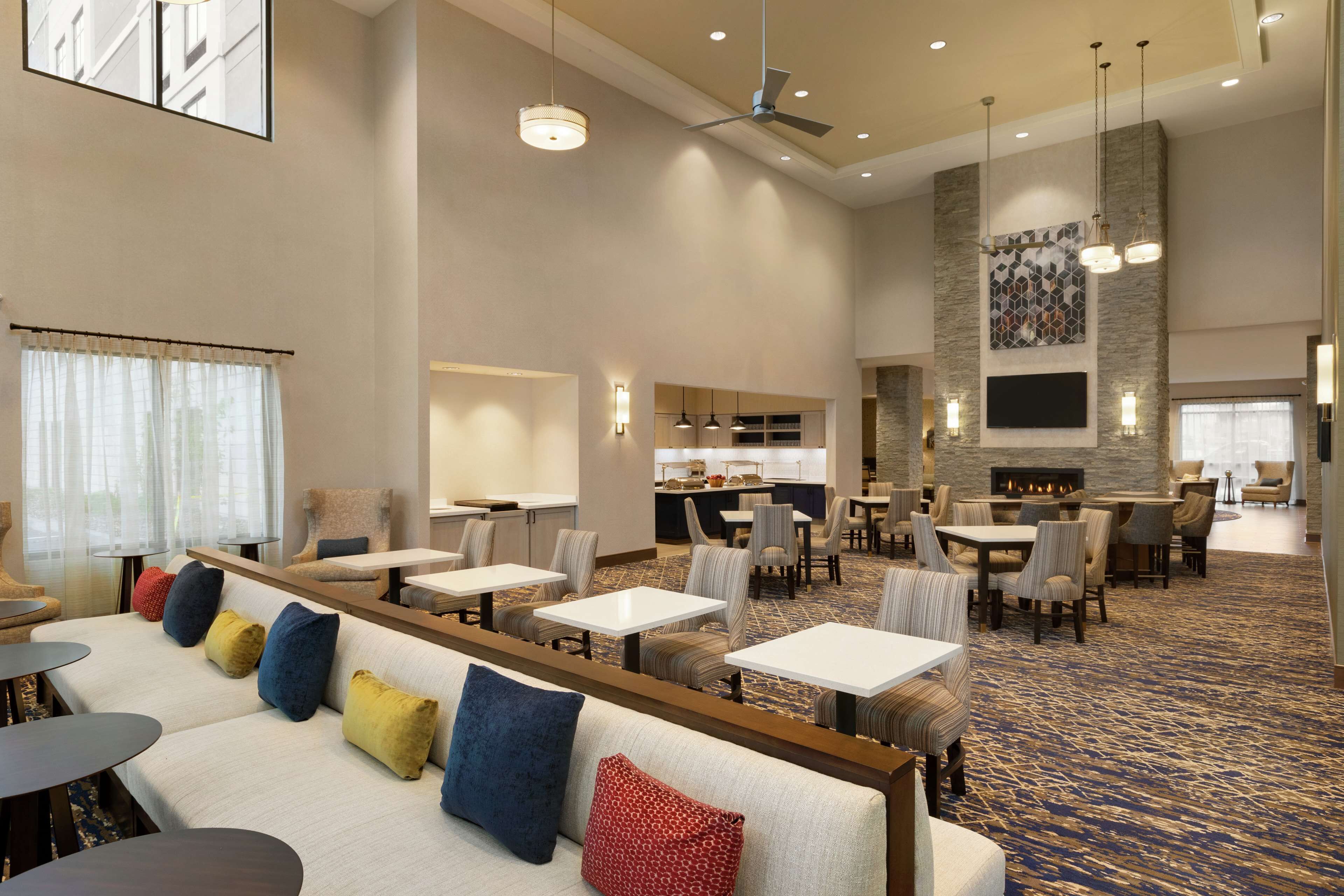 A spacious hotel lobby with multiple seating areas, a fireplace, and a television mounted on the wall.