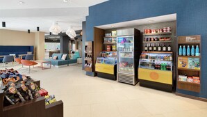 Un moderno vestíbulo de hotel con áreas de estar, un puesto de bebidas y una exhibición de aperitivos y bebidas.