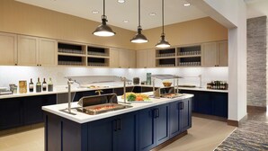 Una cocina moderna con una isla central, estantes empotrados e iluminación colgante.