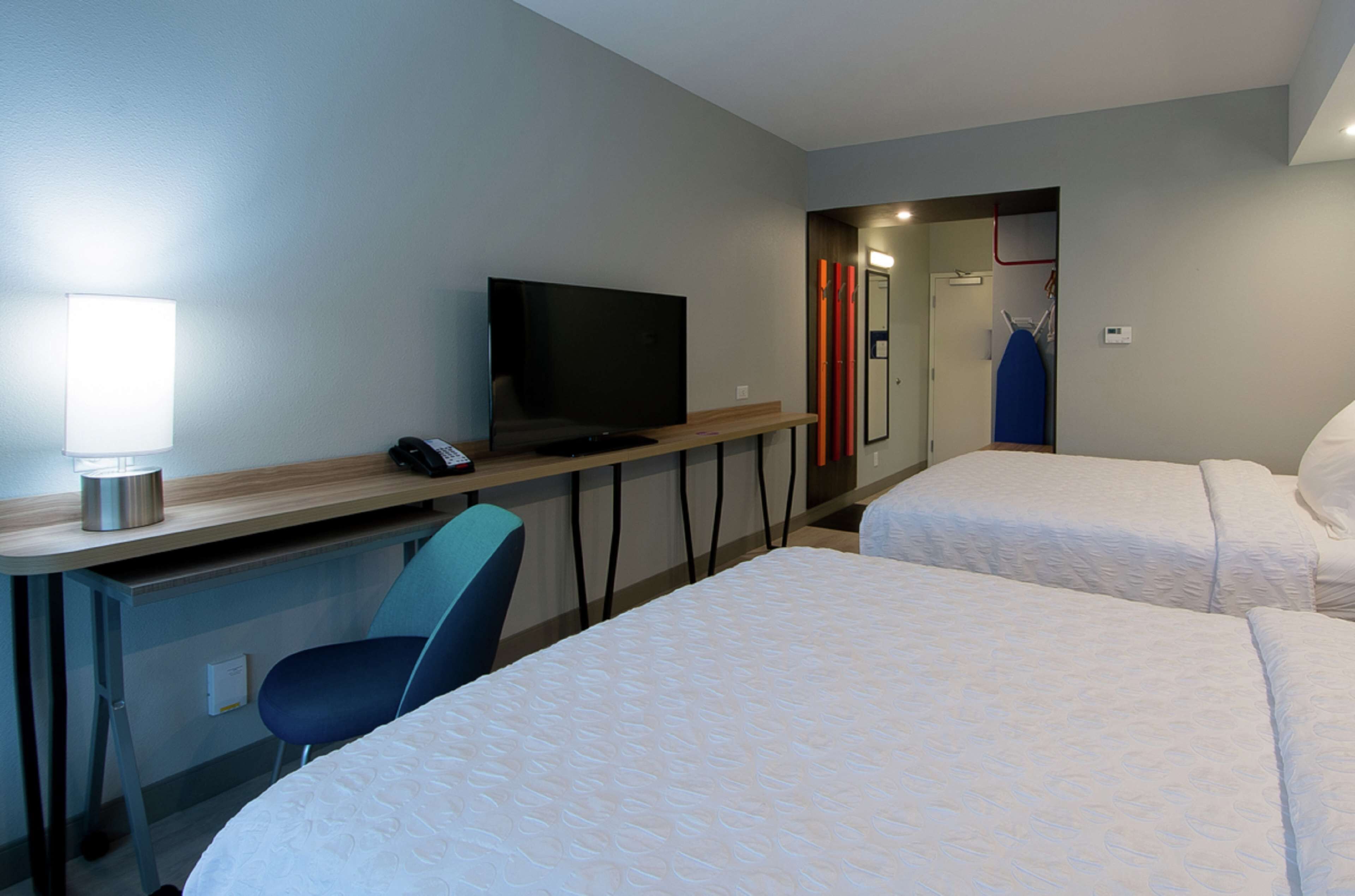Una habitación de hotel con escritorio, televisión, dos camas y una silla.
