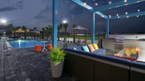 An outdoor pool area with seating and a barbecue grill.