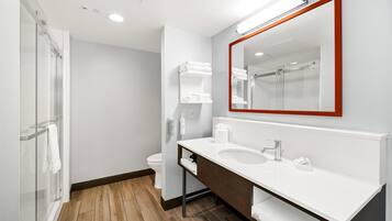 A modern bathroom with a white sink, a large mirror with a red frame, and a glass shower enclosure.
