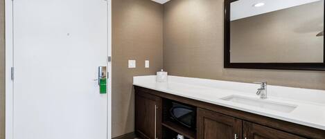 A bathroom with a white sink, dark wooden cabinets, a large mirror, and a white door.