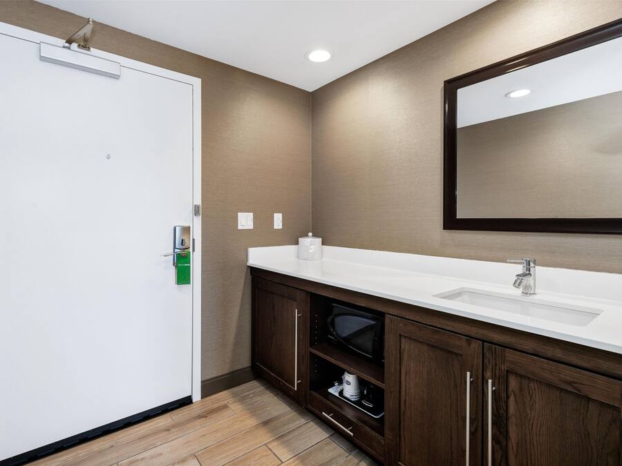 A bathroom with a white sink, dark wooden cabinets, a large mirror, and a white door.