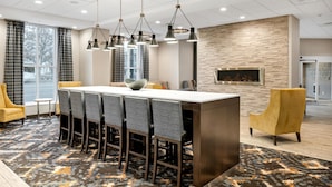 A modern hotel lobby with a large reception desk, multiple seating areas, and a fireplace. - Hampton Inn & Suites Logan (Logan)