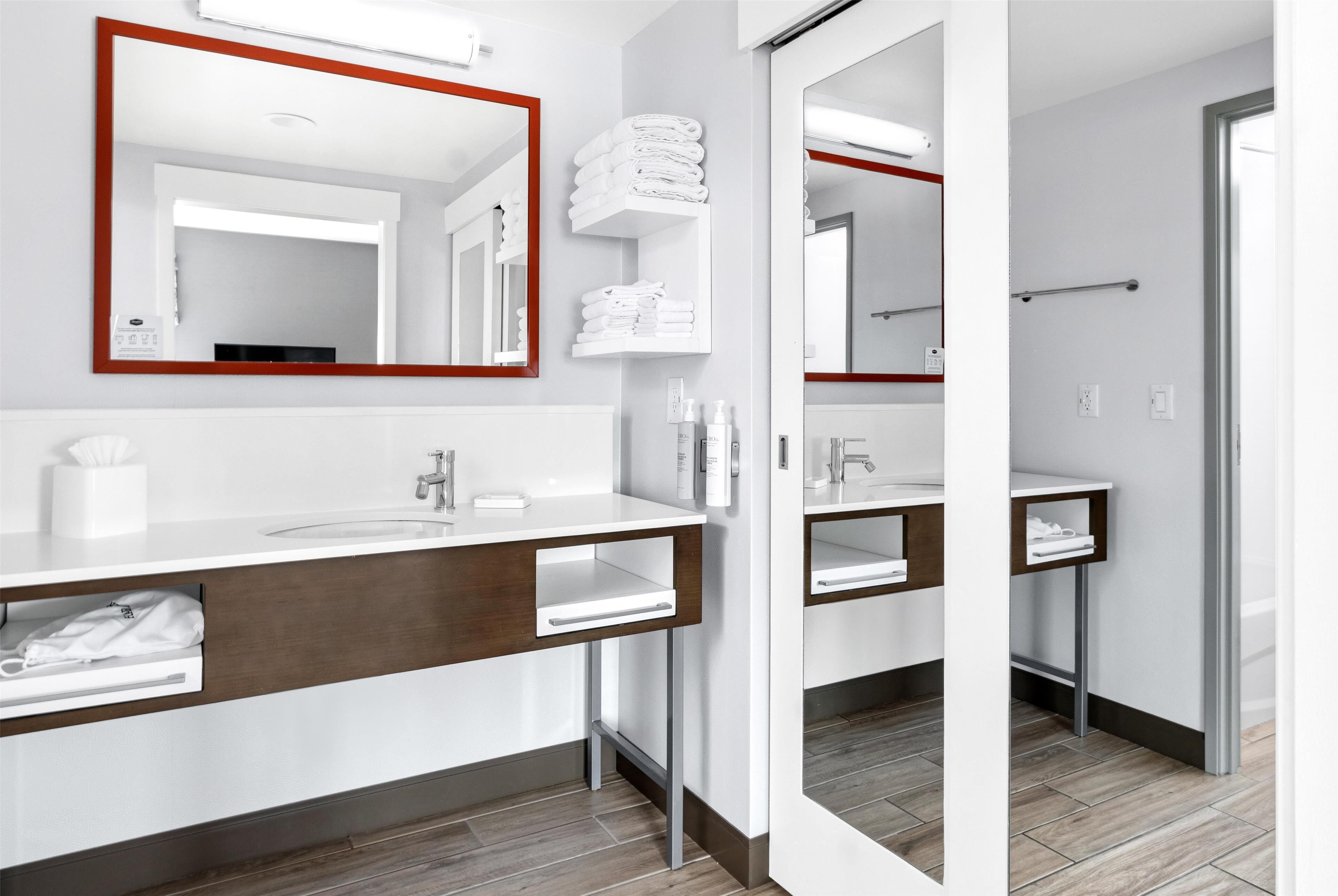 A modern bathroom with a large mirror, two sinks, and a towel rack.