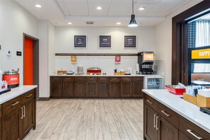 A modern kitchen with wooden cabinets, a coffee machine, and a breakfast bar. - Hampton Inn & Suites Logan (Logan)