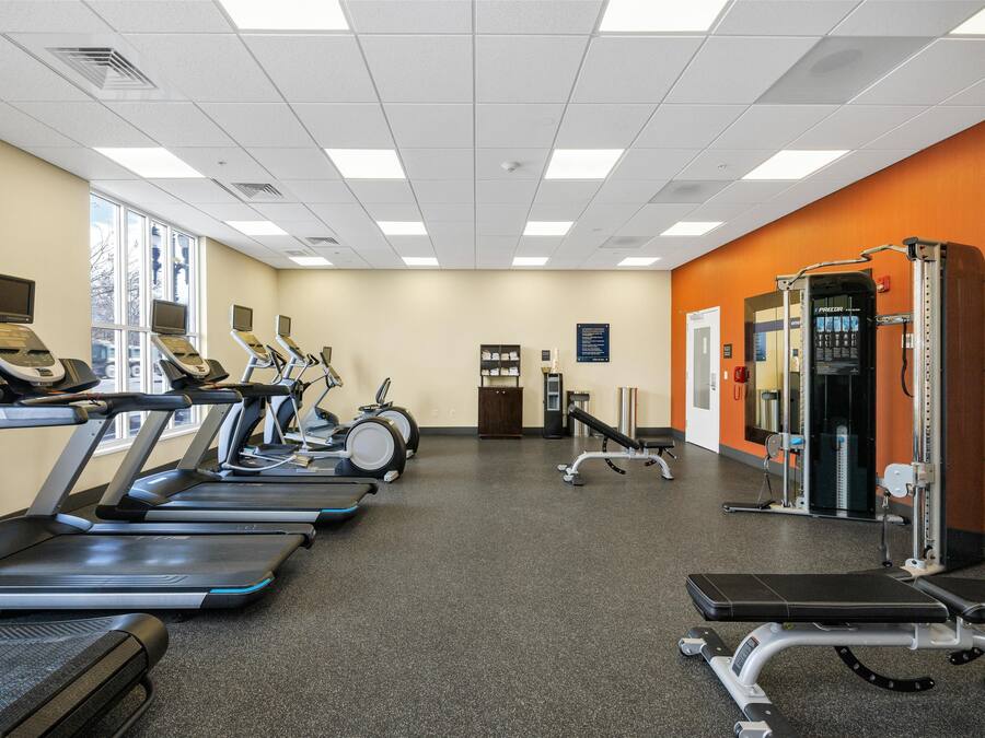 A gym with treadmills, elliptical machines, and weightlifting equipment.