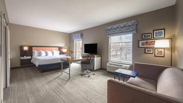 Una habitación de hotel con cama, escritorio, silla y sofá.